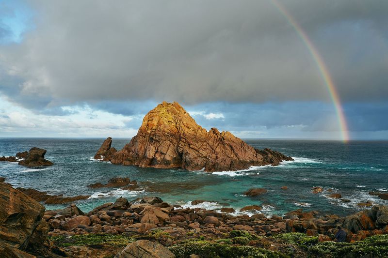 Granite rock under a storm sky and rainbow, Sugarloaf Rock, Cape Naturaliste
